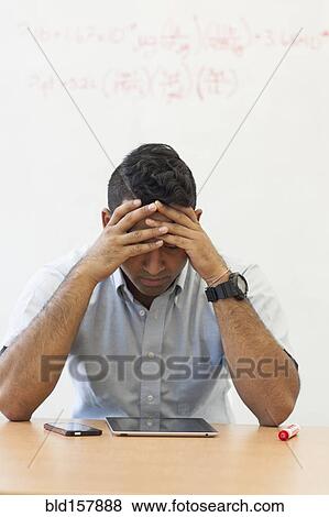 Stock Photo - Frustrated Asian businessman with digital tablet and cell phone. Fotosearch