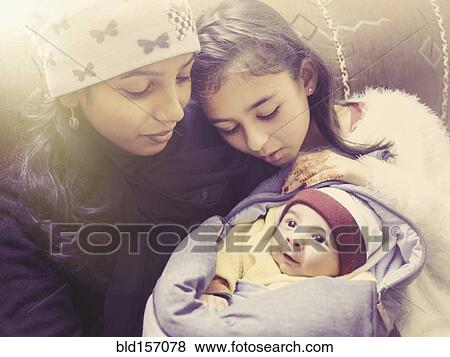 Stock Photo - Girl admiring baby nephew with aunt. Fotosearch