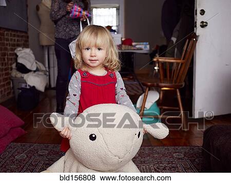 Girl playing with plush toy in living room View Large Photo Image Stock Photo - Girl playing with plush toy in living room. Fotosearch