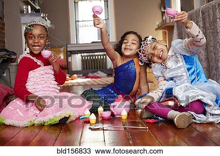 Stock Image - Girls playing dress-up and posing at tea party. Fotosearch