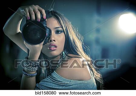 Stock Image - Glamorous woman photographer holding camera. Fotosearch