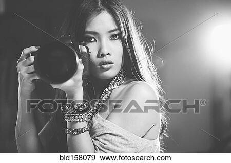 Stock Photo - Glamorous woman photographer holding camera. Fotosearch
