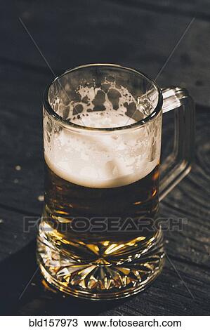 Stock Image - Glass of beer on table. Fotosearch
