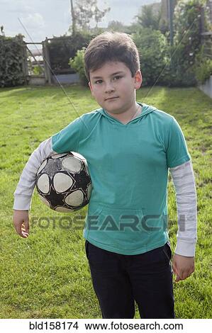 Hispanic boy holding soccer ball in backyard View Large Photo Image Picture - Hispanic boy holding soccer ball in backyard. Fotosearch