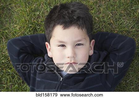 Stock Photo - Hispanic boy laying in grass. Fotosearch