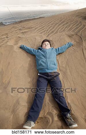 Hispanic boy laying on sand dune at beach View Large Photo Image Stock Image - Hispanic boy laying on sand dune at beach. Fotosearch