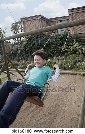 Stock Image - Hispanic boy playing on swing in backyard. Fotosearch