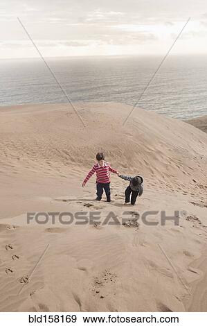 Hispanic brothers climbing on sand dunes on beach View Large Photo Image Stock Photo - Hispanic brothers climbing on sand dunes on beach. Fotosearch