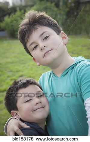 Stock Photo - Hispanic brothers hugging in backyard. Fotosearch