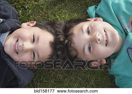 Hispanic brothers laying head to head in grass View Large Photo Image Stock Photo - Hispanic brothers laying head to head in grass. Fotosearch
