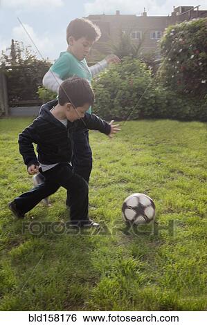 Hispanic brothers playing with soccer ball in backyard View Large Photo Image Stock Photograph - Hispanic brothers playing with soccer ball in backyard. Fotosearch