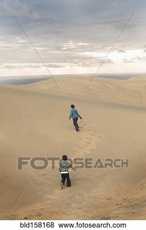 Hispanic brothers running on sand dunes View Large Photo Image Stock Photo - Hispanic brothers running on sand dunes. Fotosearch