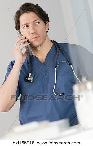 Stock Photograph - Hispanic doctor talking on cell phone in hospital. Fotosearch