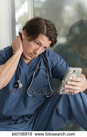 Hispanic doctor texting on cell phone in hospital View Large Photo Image Stock Photo - Hispanic doctor texting on cell phone in hospital. Fotosearch