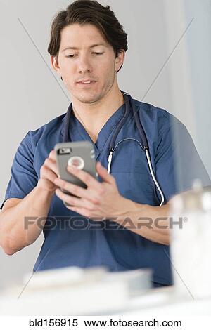 Stock Photography - Hispanic doctor texting on cell phone in hospital. Fotosearch