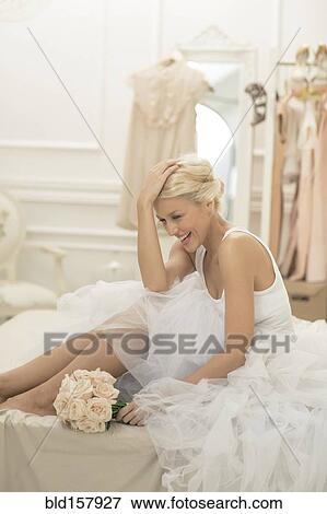 Laughing bride sitting with bouquet on bed View Large Photo Image Stock Photo - Laughing bride sitting with bouquet on bed. Fotosearch