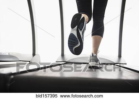 Stock Photography - Legs of mixed race woman running on treadmill. Fotosearch