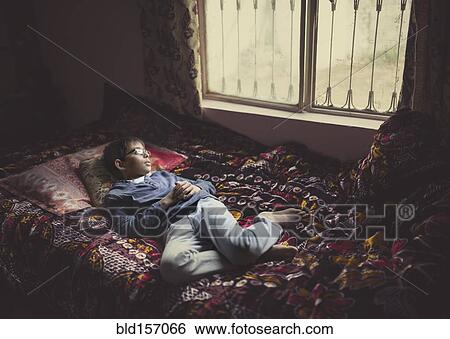 Mixed race boy looking out bedroom window View Large Photo Image Stock Photograph - Mixed race boy looking out bedroom window. Fotosearch