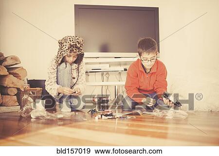 Stock Photo - Mixed race brother and sister playing on living room floor. Fotosearch