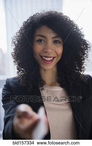 Picture - Mixed race businesswoman offering business card in office. Fotosearch
