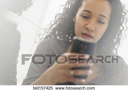 Stock Photography - Mixed race businesswoman using cell phone. Fotosearch
