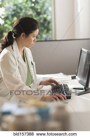 Stock Photo - Mixed race doctor working on computer in hospital. Fotosearch