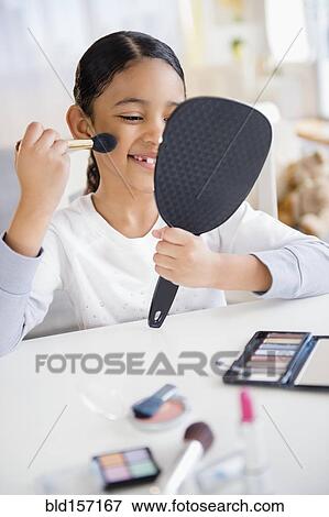 Stock Photo - Mixed race girl applying makeup with brush. Fotosearch