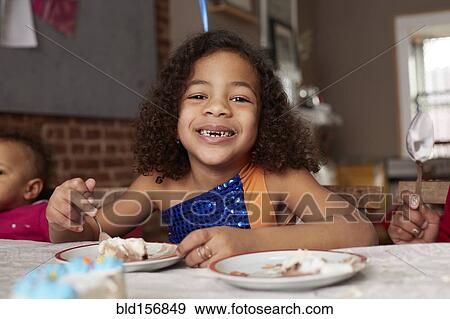 Stock Photo - Mixed race girl eating cake at table. Fotosearch