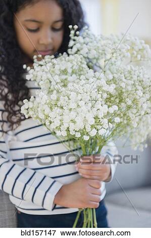 Stock Photo - Mixed race girl holding bouquet of flowers. Fotosearch