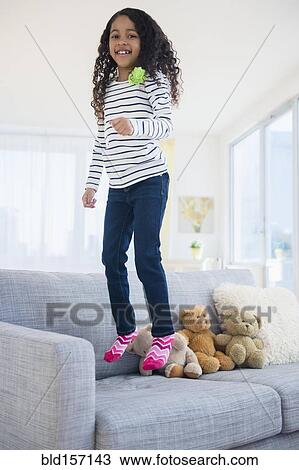 Mixed race girl jumping on sofa View Large Photo Image Stock Image - Mixed race girl jumping on sofa. Fotosearch