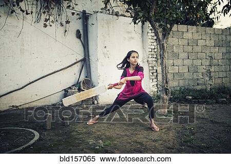 Stock Photography - Mixed race girl playing cricket near wall. Fotosearch