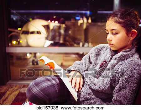 Stock Photography - Mixed race girl reading book in airport. Fotosearch