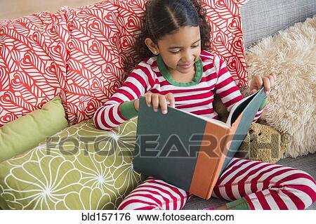 Mixed race girl reading book on sofa View Large Photo Image Stock Photograph - Mixed race girl reading book on sofa. Fotosearch