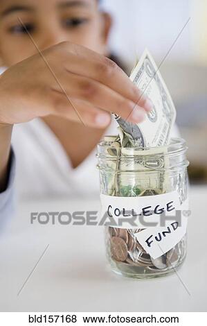 Mixed race girl saving money in college fund jar View Large Photo Image Stock Photo - Mixed race girl saving money in college fund jar. Fotosearch