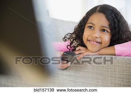 Mixed race girl watching television on sofa View Large Photo Image Stock Photo - Mixed race girl watching television on sofa. Fotosearch