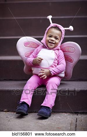 Mixed race girl wearing pink butterfly Halloween costume on staircase View Large Photo Image Stock Image - Mixed race girl wearing pink butterfly Halloween costume on staircase. Fotosearch