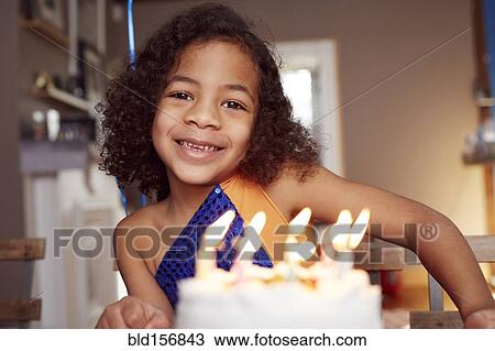 Stock Image - Mixed race girl with cake and candles. Fotosearch