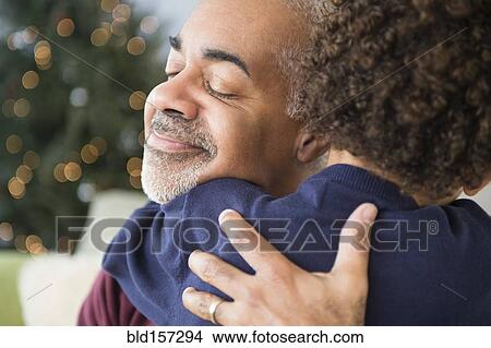 Picture - Mixed race grandfather and grandson hugging at Christmas. Fotosearch