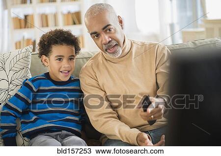Stock Image - Mixed race grandfather and grandson watching television. Fotosearch