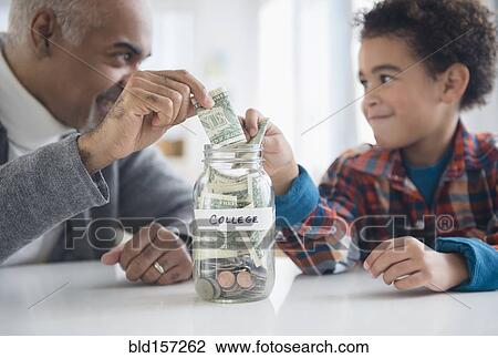 Mixed race grandfather and grandson saving money in college fund jar View Large Photo Image Stock Image - Mixed race grandfather and grandson saving money in college fund jar. Fotosearch