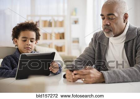 Mixed race grandfather and grandson using cell phone and digital tablet View Large Photo Image Stock Image - Mixed race grandfather and grandson using cell phone and digital tablet. Fotosearch