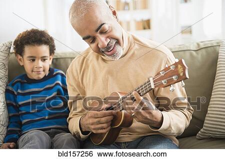 Stock Photograph - Mixed race grandfather and grandson playing ukulele. Fotosearch