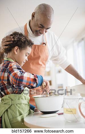 Stock Photograph - Mixed race grandfather and grandson baking in kitchen. Fotosearch