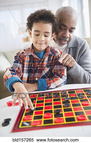Stock Photography - Mixed race grandfather and grandson playing checkers. Fotosearch