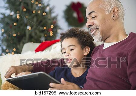 Mixed race grandfather and grandson using digital tablet at Christmas View Large Photo Image Stock Photography - Mixed race grandfather and grandson using digital tablet at Christmas. Fotosearch
