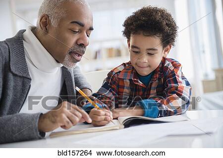 Picture - Mixed race grandfather helping grandson do homework. Fotosearch