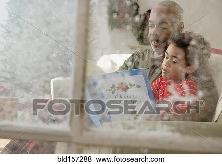 Mixed race grandfather reading to grandson behind window at Christmas View Large Photo Image Stock Photo - Mixed race grandfather reading to grandson behind window at Christmas. Fotosearch