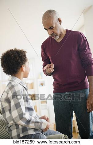 Stock Photo - Mixed race grandfather scolding grandson. Fotosearch