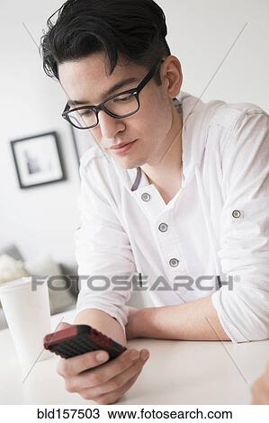 Stock Image - Mixed race man texting on cell phone. Fotosearch