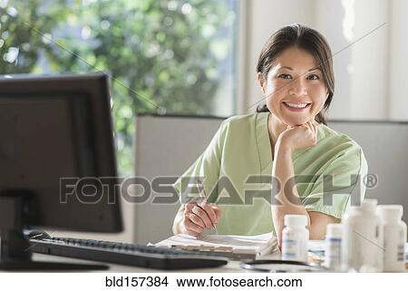Mixed race nurse posing with computer in hospital View Large Photo Image Picture - Mixed race nurse posing with computer in hospital. Fotosearch